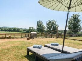 An outdoor area with sun loungers and umbrella at Piglet Corner in Culmstock