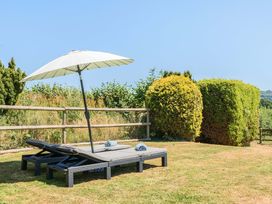 A garden with lounge chairs and an umbrella at Piglet Corner in Culmstock