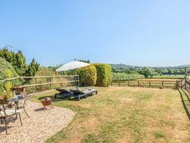 A garden with sun loungers and a table at Piglet Corner in Culmstock