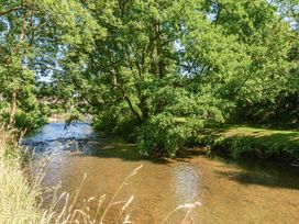 A river surrounded by trees and grass at Piglet Corner in Culmstock
