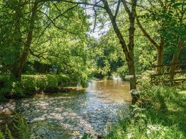 A river surrounded by trees and grass at Piglet Corner in Culmstock