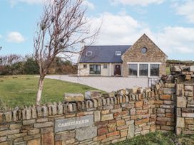 A house with a gravel driveway and stone wall at Cashelrehin in Falcarrheh