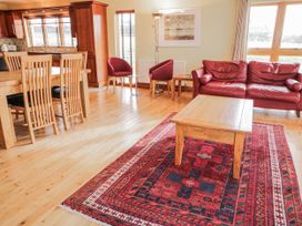 A living room with a dining area and red sofa at Cashelrehine Falcarrheh