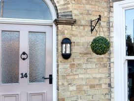 A front door with textured glass panels number 14 and a black lantern and hanging green plant on brick wall at Thorncliffe House in Pocklington