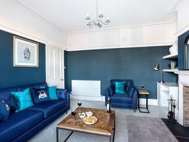 A living room with blue sofa and armchair a wooden coffee table with snacks and wine glasses at Thorncliffe House in Pocklington