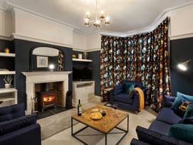 A living room with a lit fireplace blue sofas a wooden coffee table with snacks and wine at Thorncliffe House in Pocklington