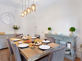 A dining room with a wooden table set with plates wine glasses and food and grey chairs at Thorncliffe House in Pocklington