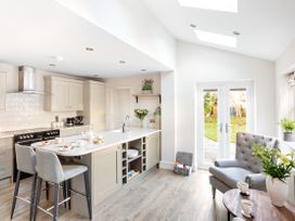 A kitchen with a breakfast bar, two chairs, and an armchair near glass doors opening to a garden at Thorncliffe House in Pocklington
