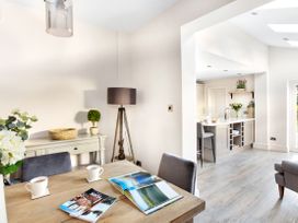 A dining area with a wooden table and two chairs next to a white sideboard with a lamp and plant in an open kitchen living space at Thorncliffe House in Pocklington
