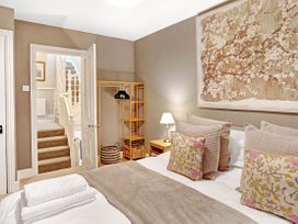 A bedroom with a bed pillows bedside table lamp open door and stairs at Thorncliffe House in Pocklington