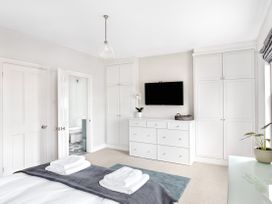 A bedroom with a bed folded towels white wardrobes a wall-mounted TV and a door leading to a bathroom at Thorncliffe House in Pocklington