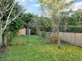 A garden with trees a wooden shed and a metal garden arch on grass at Thorncliffe House in Pocklington