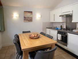 A kitchen with a wooden dining table and black chairs and white cabinets at Thorpe Forest Silver Birch in Thorpe Forest