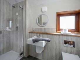 A bathroom with a shower cubicle sink with a towel on it round mirror and window at Garwnant Golden Oak in Garwnant Bannau Brycheiniog Brecon Beacons