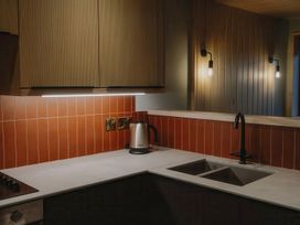 A kitchen countertop with a kettle a stove and a sink with a black faucet at Glentress The Unfurl Cabin in Glentress Forest Peebles