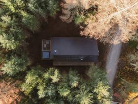 An aerial view of a rectangular cabin surrounded by trees with a path nearby at Glentress The Unfurl Cabin (2 doubles 1 twin) in Glentress Forest Peebles