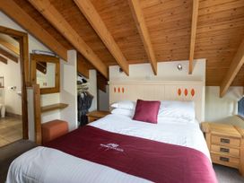 A bedroom with a double bed bedside tables and wooden ceiling beams at Deerpark Classic Golden Oak Treehouse in Deerpark Forest