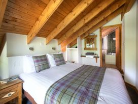 A bedroom with a bed under a sloped wooden ceiling and an open door leading to a bathroom at Strathyre Classic Golden Oak in Strathyre Ben Ledi