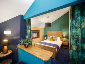 A bedroom with a wooden bed frame a blue and green wall and a wooden shelf at Strathyre Golden Oak Hideaway Strathyre Ben Ledi
