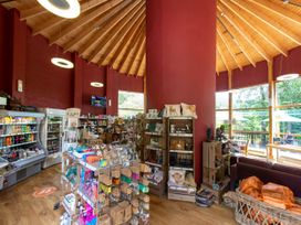 A shop interior with wooden shelves and displays holding various items including pillows and snacks at Strathyre Golden Oak Hideaway in Strathyre Ben Ledi