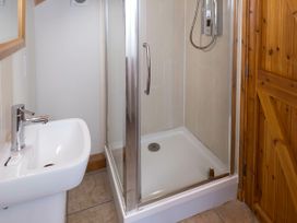 A bathroom with a white sink and a glass shower enclosure with wooden door at Keldy Classic Golden Oak in Keldy Forest