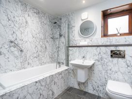 A bathroom with a bathtub shower sink toilet round mirror and window at Keldy White Willow Premium in Keldy Forest