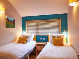 A bedroom with two single beds separated by a wooden nightstand and a window with blinds at Beddgelert Golden Oak - freshly inspired design Beddgelert Eryri Snowdonia