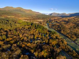 An aerial view of a wooded valley with scattered buildings and a winding road at Beddgelert Golden Oak - freshly inspired design in Beddgelert Eryri Snowdonia