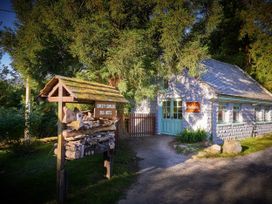 A stone building with blue windows and a wooden bug hotel structure outside at Beddgelert Golden Oak - freshly inspired design in Beddgelert Eryri Snowdonia