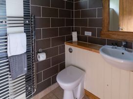 A bathroom with a toilet sink mirror towel rack and dark tiled walls at Keldy Classic Golden Oak in Keldy Forest