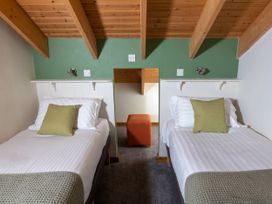 A bedroom with two single beds with green cushions and a wooden ceiling at Keldy Classic Golden Oak in Keldy Forest