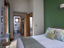 A bedroom with a bed next to a green wall and an open door showing a bathroom at Strathyre New Style Golden Oak Strathyre Ben Ledi