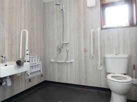 A bathroom with a toilet sink shower and support rails at Glentress Forest Silver Birch wheelchair accessible cabin in Peebles