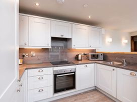 A kitchen with white cabinets a stove oven microwave kettle and sink at Glentress Forest White Willow Premium in Glentress Forest Peebles
