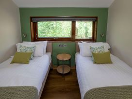 A bedroom with two single beds and a round wooden side table under a window at Garwnant Golden Oak Treehouse in Garwnant Bannau Brycheiniog Brecon Beacons