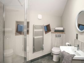 A bathroom with a toilet a sink with a towel a round mirror and a small window at Garwnant Golden Oak Treehouse in Garwnant Bannau Brycheiniog Brecon Beacons