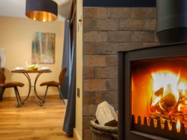 A dining area with a table and two chairs and a burning wood stove in a room at Strathyre Golden Oak Hideaway Strathyre Ben Ledi