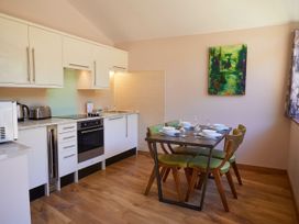 A kitchen with white cabinets countertop appliances and a dining table set with four green chairs and dishware at Beddgelert Silver Birch - freshly inspired design Beddgelert Eryri Snowdonia