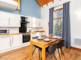 A kitchen with a wooden dining table set with plates and glasses next to a window with curtains at Keldy Classic Silver Birch in Keldy Forest