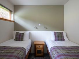 A bedroom with two single beds separated by a wooden nightstand at Strathyre Classic Golden Oak in Strathyre Ben Ledi