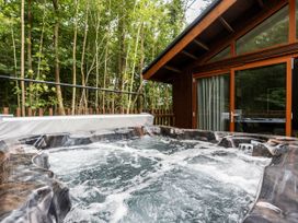 An outdoor hot tub with bubbling water next to a wooden cabin surrounded by trees at Strathyre New Style Silver Birch in Strathyre Ben Ledi