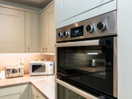 A kitchen with built-in oven toaster microwave and white cabinets at Strathyre New Style Silver Birch in Strathyre Ben Ledi