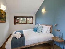 A bedroom with a bed with pillows and towels next to a window showing trees at Strathyre New Style Silver Birch in Strathyre Ben Ledi