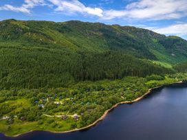 A lakeside area with trees and wooden cabins at Strathyre Classic Golden Oak in Strathyre Ben Ledi