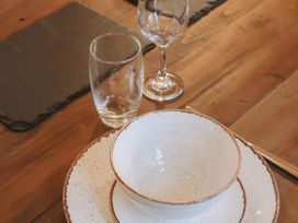 A table setting with a bowl on a plate and two glasses on a wooden table at Glentress The Unfurl Treehouse in Glentress Forest Peebles