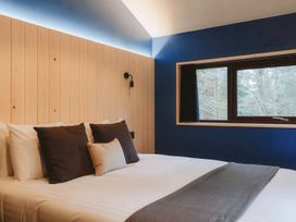 A bedroom with a bed with pillows and a window showing trees at Glentress The Unfurl Treehouse in Glentress Forest Peebles