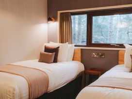 A bedroom with two single beds separated by a wooden stool under a window at Glentress The Unfurl Treehouse Glentress Forest Peebles