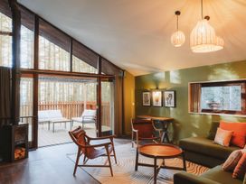 A living room with wooden chairs and a sofa next to a deck with outdoor seating at Glentress The Unfurl Treehouse in Glentress Forest Peebles