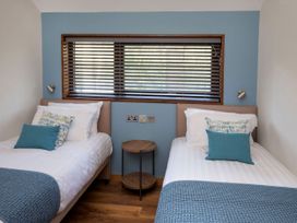 A bedroom with two single beds a small round table between them and a window with blinds at Ardgartan Argyll Silver Birch in Ardgartan Loch Long