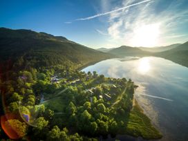 A lakeside village surrounded by trees and hills under a bright sky at Ardgartan Argyll Silver Birch in Ardgartan Loch Long